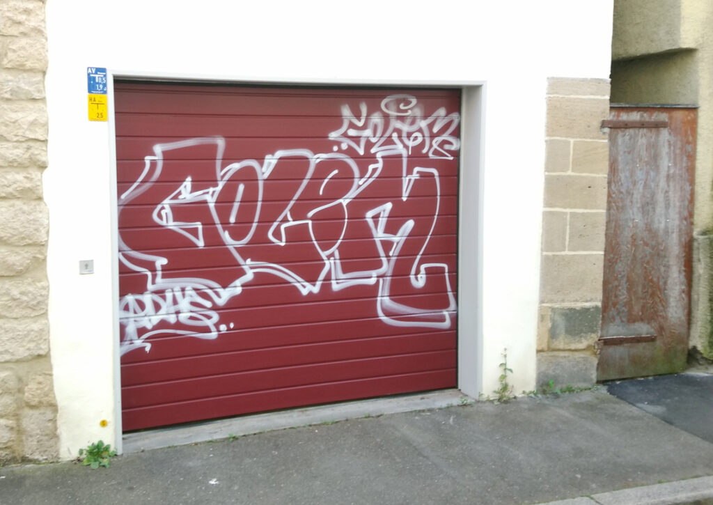 ein weißes Graffiti wurde auf ein rotes Garagentor gesprüht