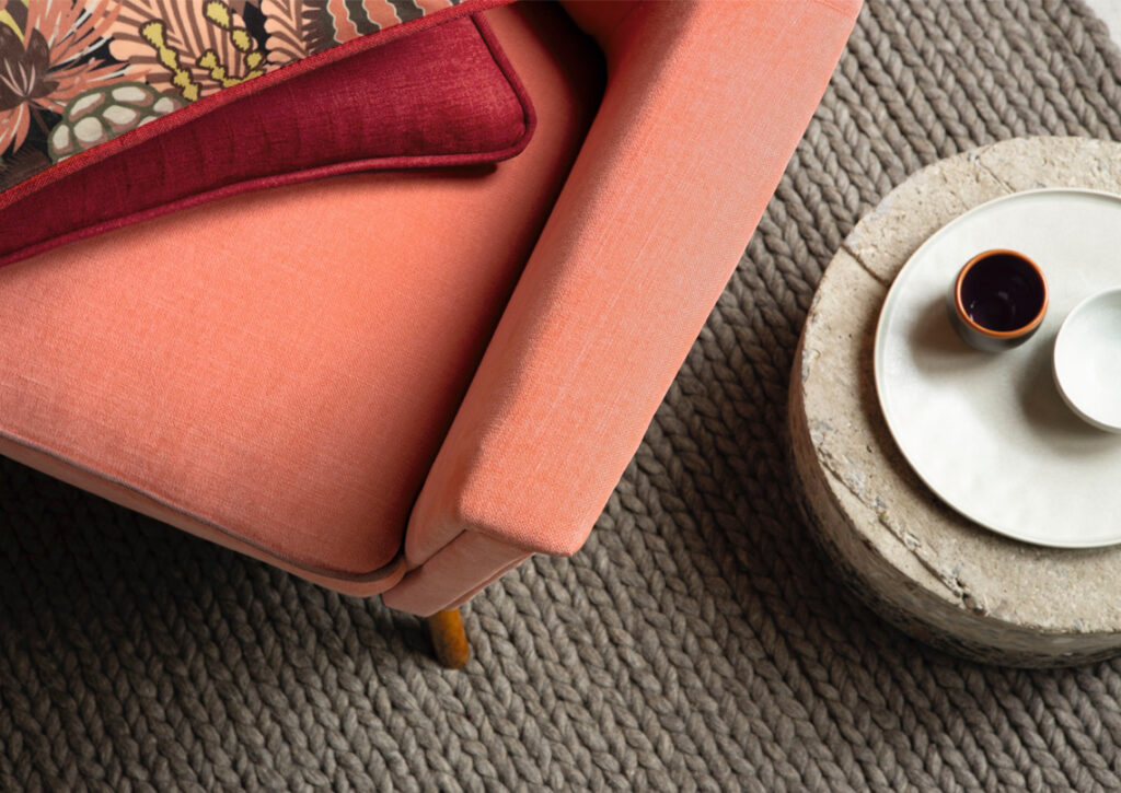 lachfarbenes Sofa mit braunen grob geflochtenen Teppich darunter