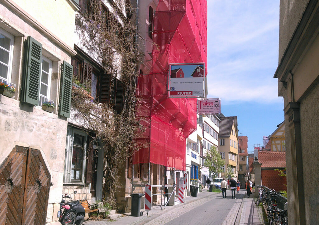 Haus in Fußgängerzone mit Gerüst und rotem Netz davor
